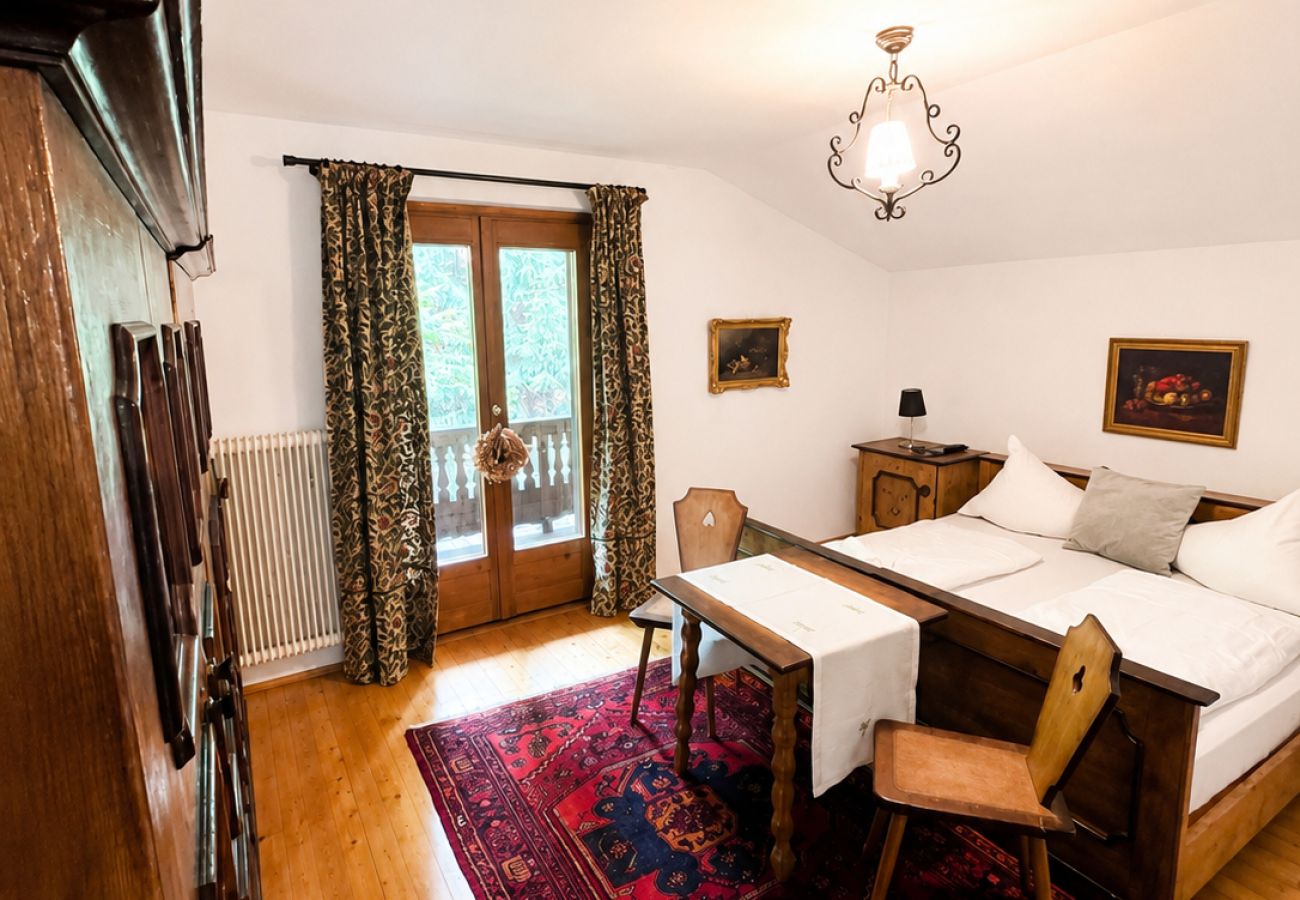 Bedroom in Kirchberg in Tirol chalet with double bed, small table, chairs, wooden walls and balcony