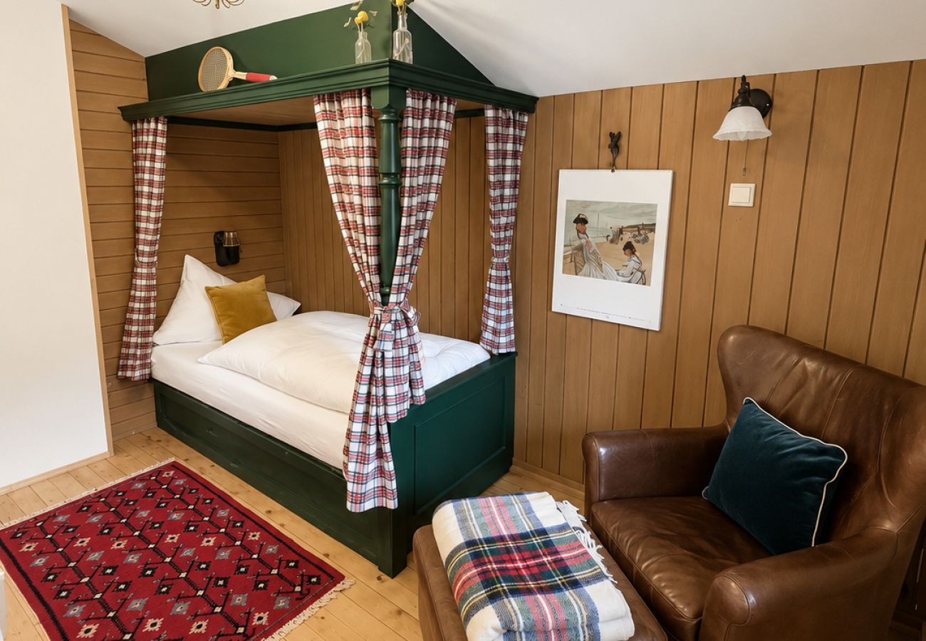 Kleines Schlafzimmer im Chalet Kirchberg in Tirol mit Einzel-Himmelbett, Holzwänden, karierten Vorhängen und Teppich