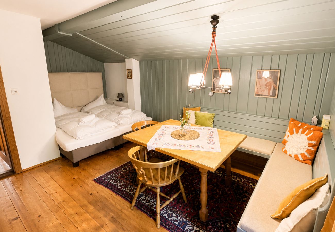 Eckbank mit Tisch und Schlafbereich im Chalet Kirchberg in Tirol mit Holzboden, Hängelampen und gemütlicher Sitzecke